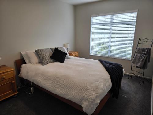a bedroom with a bed with pillows and a window at Beautiful 3 bedroom apartment, only steps to the golden sand in Kaiteriteri