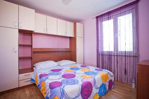 ein Schlafzimmer mit einem großen Bett mit einer farbenfrohen Tagesdecke in der Unterkunft Apartments Villa Leona in Betina