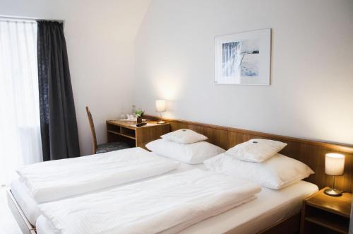 two beds in a hotel room with white sheets at Hotel Blaue Traube in Schongau