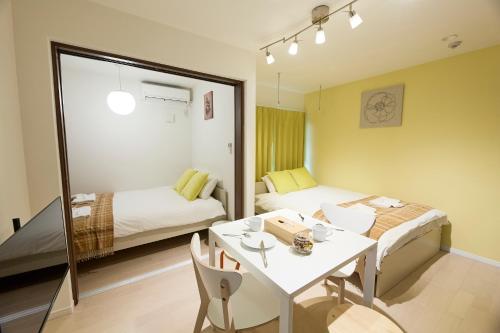 a room with two beds and a table and a table and a bed at Ashe Maison Matsu II in Osaka