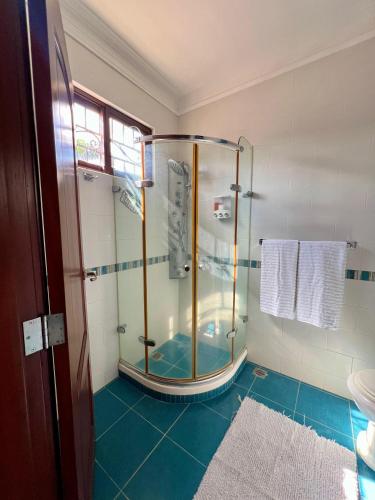 a glass shower in a bathroom with blue tiles at Villa Margarita para tú deleite.” in Concepción de La Vega