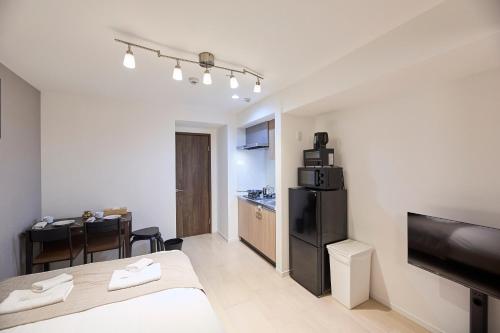 a room with a bed and a kitchen with a table at Ashe Maison Matsu II in Osaka