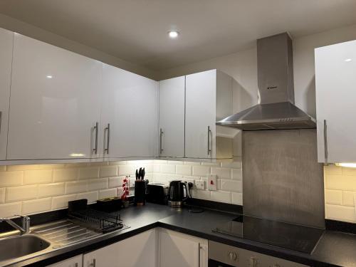 a kitchen with white cabinets and a sink at Apartment near Luton Airport, Train Station & Football Club in Luton