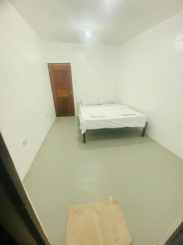 a white room with a bed and a door at Inn Convenience in Coron