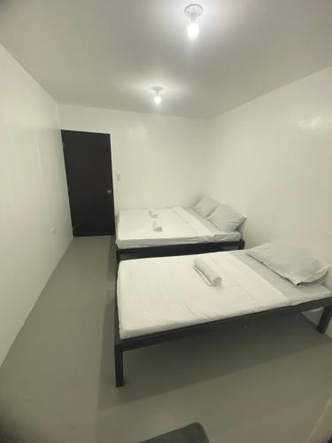 two beds sitting in a white room with at Inn Convenience in Coron