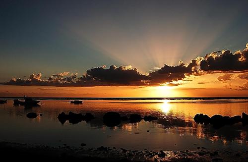 a sunset over a body of water with boats in it at Son House Studio in Flic-en-Flac