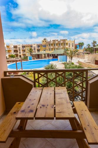 una mesa de picnic de madera en un balcón con piscina en Aparthotel Tropical Bounty Beach B11, en Santa Maria