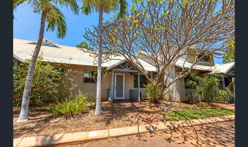 a house with palm trees in front of it at Broome - 2 Bedroom Apartment in Cable Beach