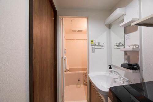 a bathroom with a sink and a bath tub at Ashe Maison Matsu II in Osaka