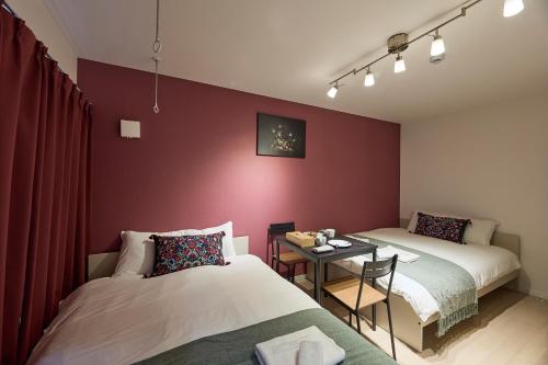 a room with two beds and a small table with a table at Ashe Maison Matsu II in Osaka