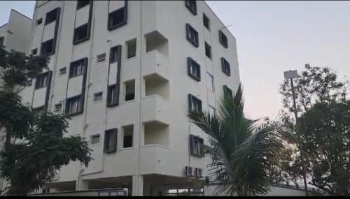a white building with a palm tree in front of it at Garudadri Home Stay in Renigunta