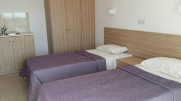 a hotel room with two beds and a sink at Simos Magic Hotel Apts in Ayia Napa