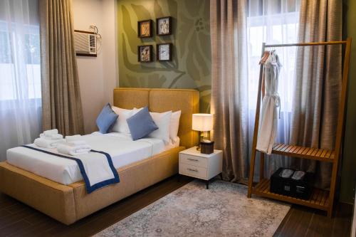 a bedroom with a bed with blue pillows and a window at UNWND Boutique Hotel Calatagan in Batangas City