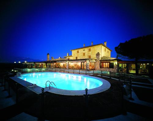 a large swimming pool in front of a building at night at Relais Todini - Residenza d'epoca - Luxury Historic house in Todi