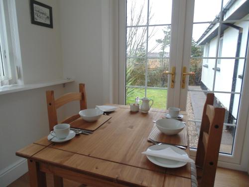 a wooden table with bowls and plates on it at Woodside Guest House in Stornoway