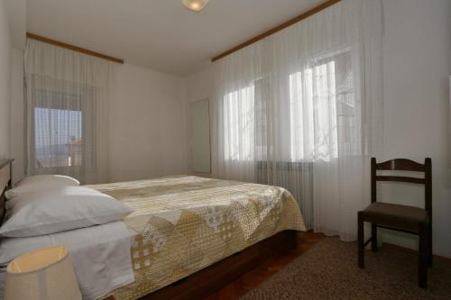a bedroom with a bed and a chair and windows at Apartments Olga in Božava