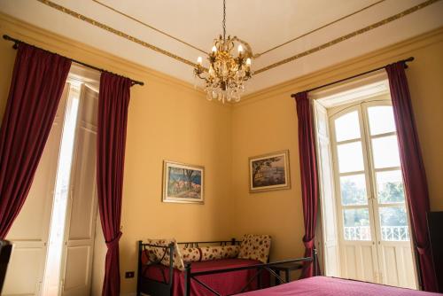 シラクーサにあるSognando Ortigiaのベッドルーム1室(シャンデリア、窓2つ付)