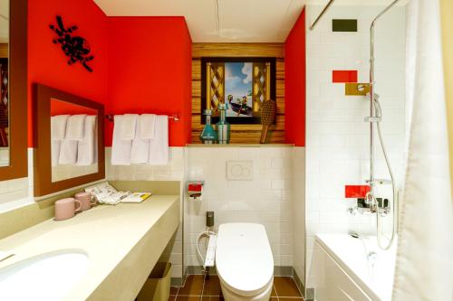 a bathroom with red walls and a toilet and a sink at LEGOLAND Korea Resort Hotel in Chuncheon