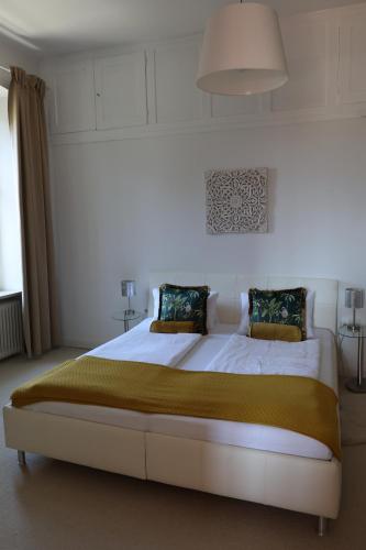 a bedroom with a large white bed with a yellow blanket at Villa Adrienne in Velden am Wörthersee