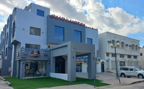 Un edificio blanco con un coche aparcado delante. en Sur Hotel, en Sur
