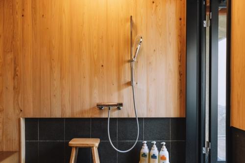 a shower in a bathroom with a wooden wall at Chikurakutei in Minami Aso