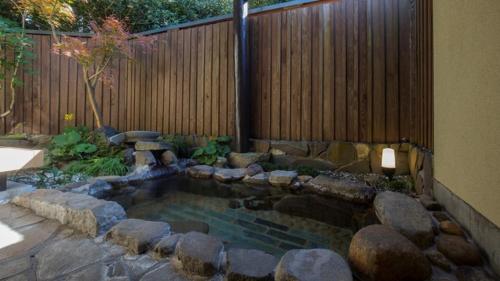 a backyard with a pond with rocks and a fence at Chikurakutei in Minami Aso