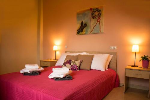 a bedroom with a red bed with towels on it at Aksos Suites Accessible Accommodation in Ayiá
