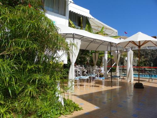 een terras met tafels en stoelen en een zwembad bij Hotel Savona in Arica