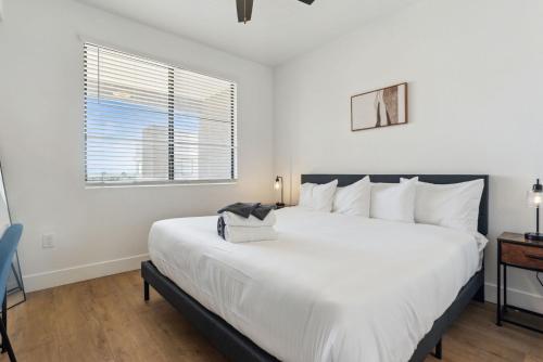 a white bedroom with a large bed and a window at CozySuites Glendale - Westgate with pool 05 in Glendale