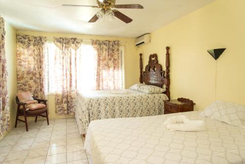 a bedroom with two beds and a ceiling fan at Villa Donna Inn in Montego Bay