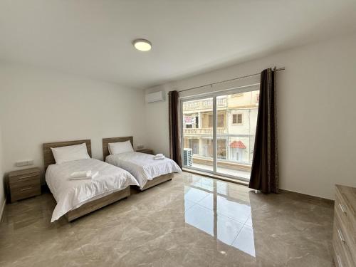 a bedroom with two beds and a large window at New Apartment! Walking distance to the three cities by SF Homes in Fgura