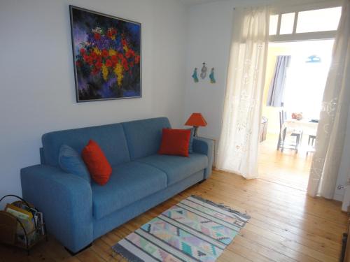 a blue couch in a living room with a painting at Guest House Dasos Kynthos in Brussels