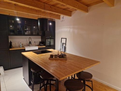 une cuisine avec une table en bois et quelques tabourets de bar dans l'établissement Maison Jade, Wifi, Terrasse, Barbecue, 10 couchages, à La Rochelle
