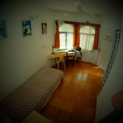 a room with a bed and a table and chairs at New Creation Guest House in Auroville