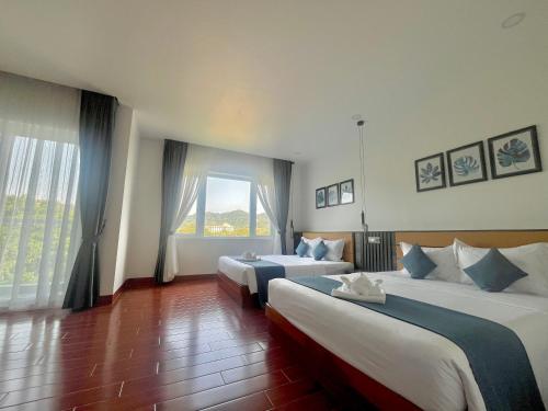 a hotel room with two beds and a large window at Kep Sea View Hotel & Sky Bar in Kep