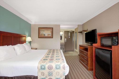 a hotel room with a bed and a flat screen tv at Ramada by Wyndham Houston Intercontinental Airport South in Houston