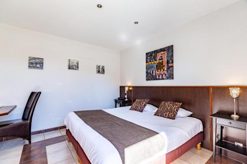 a bedroom with a bed and a desk and a chair at Logis Hôtel L'Oliveraie in Cognac