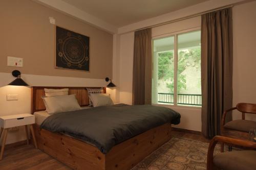 a bedroom with a large bed and a window at The Trippy Tribe Riverside Hostel Kasol in Kasol