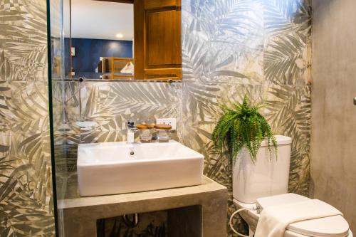 a bathroom with a sink and a toilet at UNWND Boutique Hotel Calatagan in Batangas City