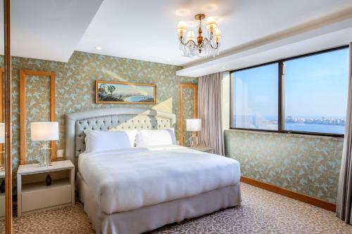 a bedroom with a white bed and a large window at Hilton Copacabana Rio de Janeiro in Rio de Janeiro