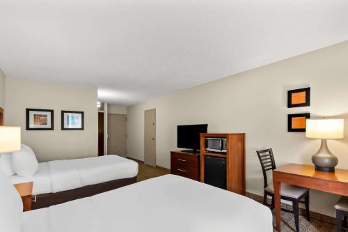 a hotel room with two beds and a desk and a tv at Comfort Inn St Louis - Westport Event Center in Maryland Heights