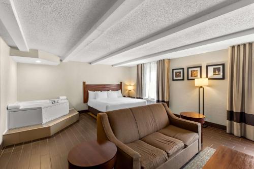 a hotel room with a bed and a couch at Comfort Inn St Louis - Westport Event Center in Maryland Heights