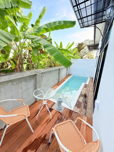 a balcony with a table and chairs and a swimming pool at Chiangmai Courtyard Residence บ้านสวนสวย บ้านถวาย in Bān Sawan