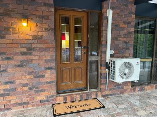 a welcome sign in front of a house with a door at Comfy Logan - Shared bathrooms - Individual Room with a Queenbed- WiFi AC Netflix in Tanah Merah
