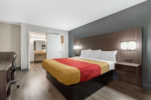 a hotel room with a bed with a red and yellow blanket at Econo Lodge in Creedmoor