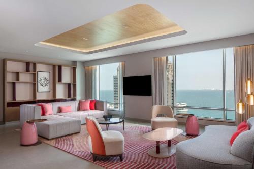 a living room with pink furniture and a large window at Andaz Doha, by Hyatt in Doha