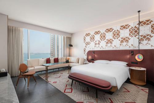 a bedroom with a large bed and a living room at Andaz Doha, by Hyatt in Doha