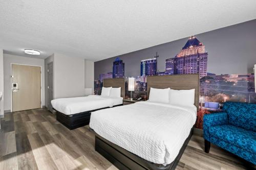 a hotel room with two beds and a blue couch at Clarion Pointe I-85 High Point - Archdale in Westwood