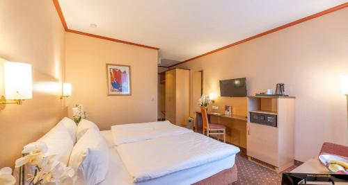 a hotel room with a bed and a desk at Sure Hotel by Best Western Hilden-Düsseldorf in Hilden