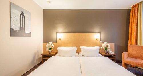 a hotel room with a bed and a chair at Sure Hotel by Best Western Hilden-Düsseldorf in Hilden